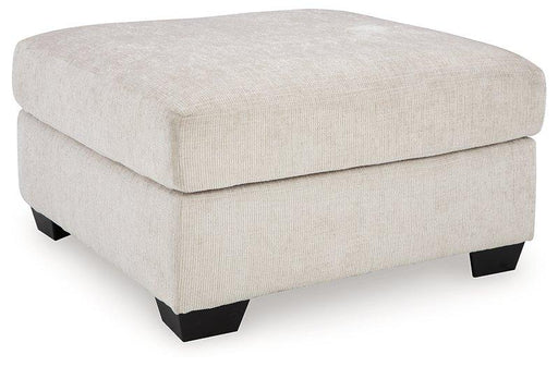 A beige oversized accent ottoman from Ashley Furniture with plush fabric and a modern design, perfect for living room decor.